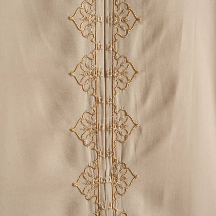 Close-up of a beige fabric with intricate gold embroidery